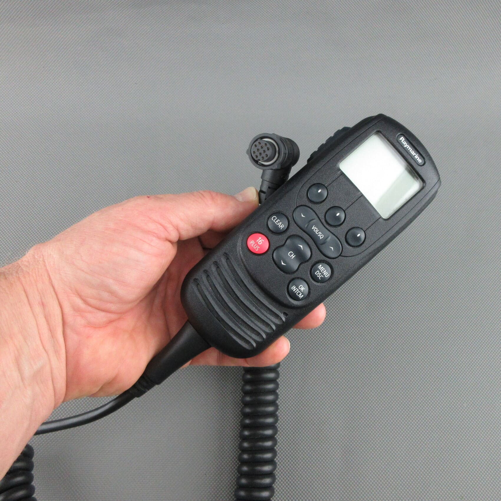Vooraanzicht van een gereviseerde Raymarine® Ray260 VHF handset A80197 in de hand, met zicht op de voorzijde en de aansluitstekker.