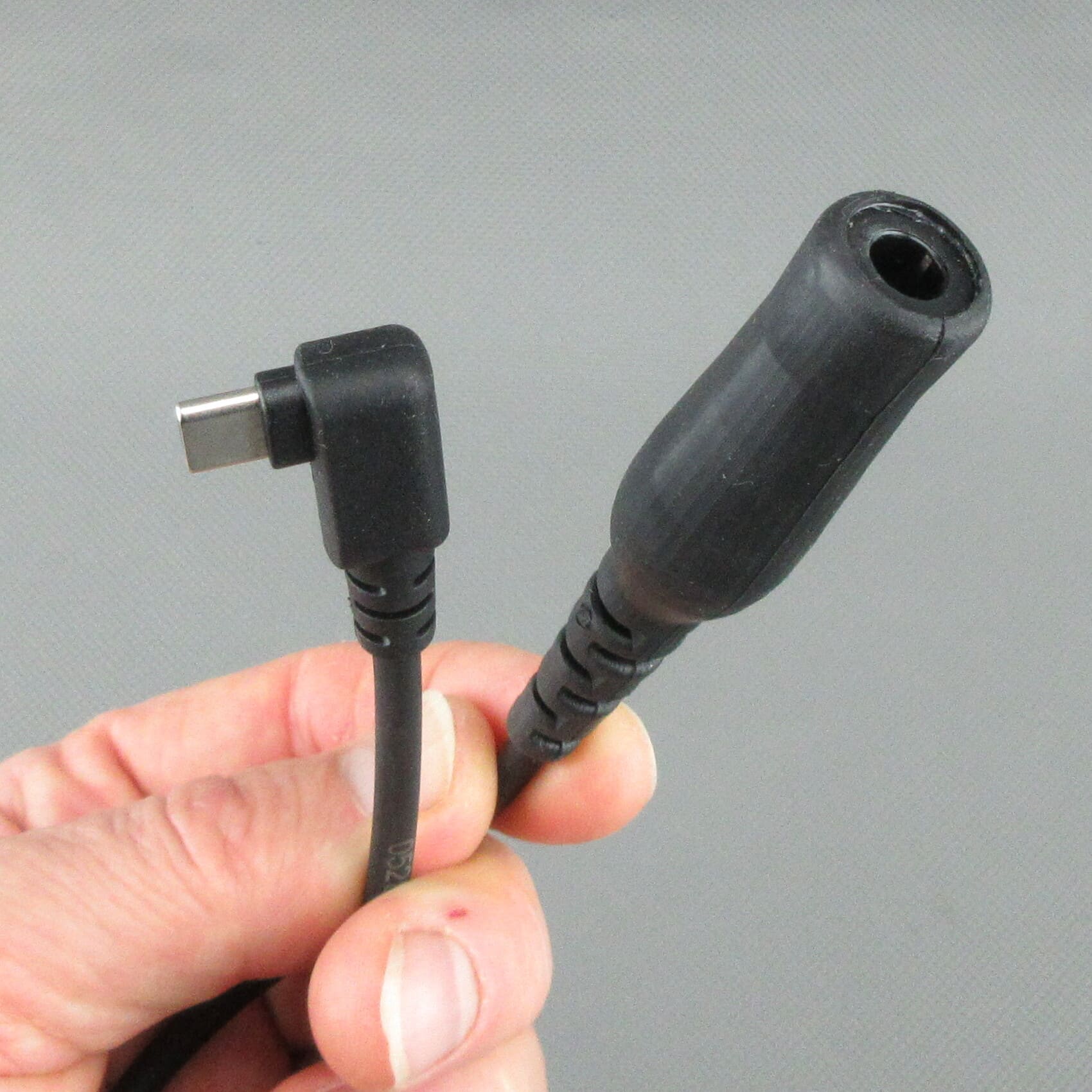 Hand die de StarCom1 FLX2 adapterkabel vasthoudt, met de focus op de haakse USB-C-stekker en de TP-120-koppelbus (compatibel met Nexus® / Amphenol®) voor het aansluiten van tactische headsets met NATO-bedrading.